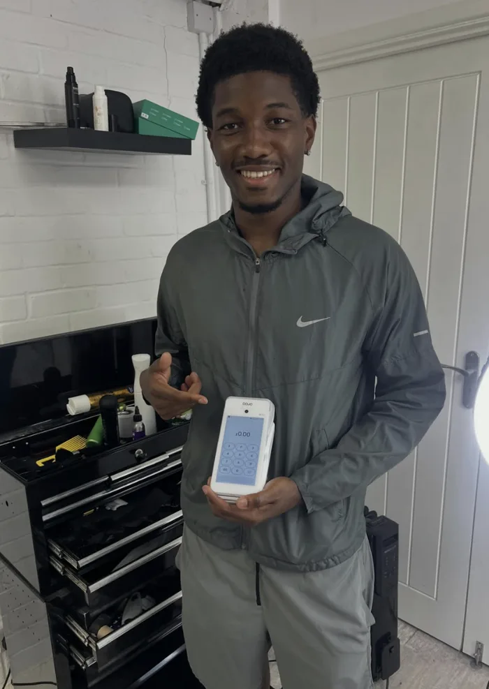Zinna of Zinna Barbers holding a Dojo card machine
